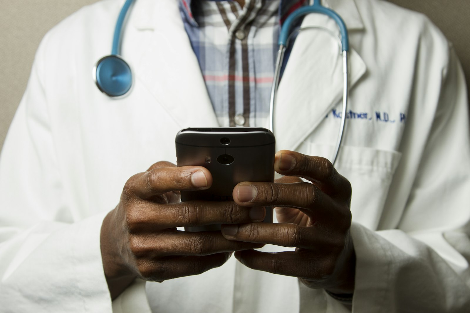 Doctor in a white coat using a mobile device between consultations